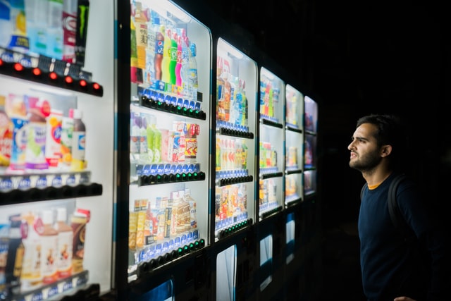 conscious consumerism man choosing from many different drinks in a vending machine